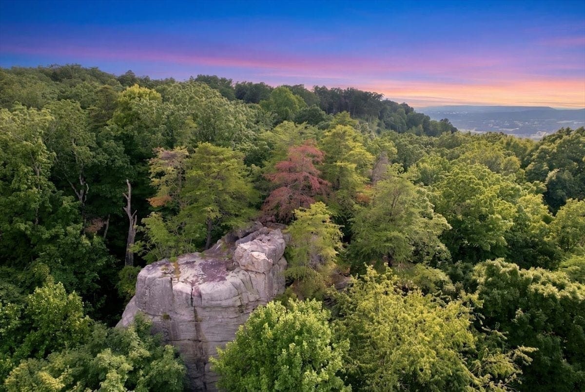 Aerial photograph of High Rock, the sandstone formation on Lot 55 catching the last light above the forested ridge and valley at sunset.